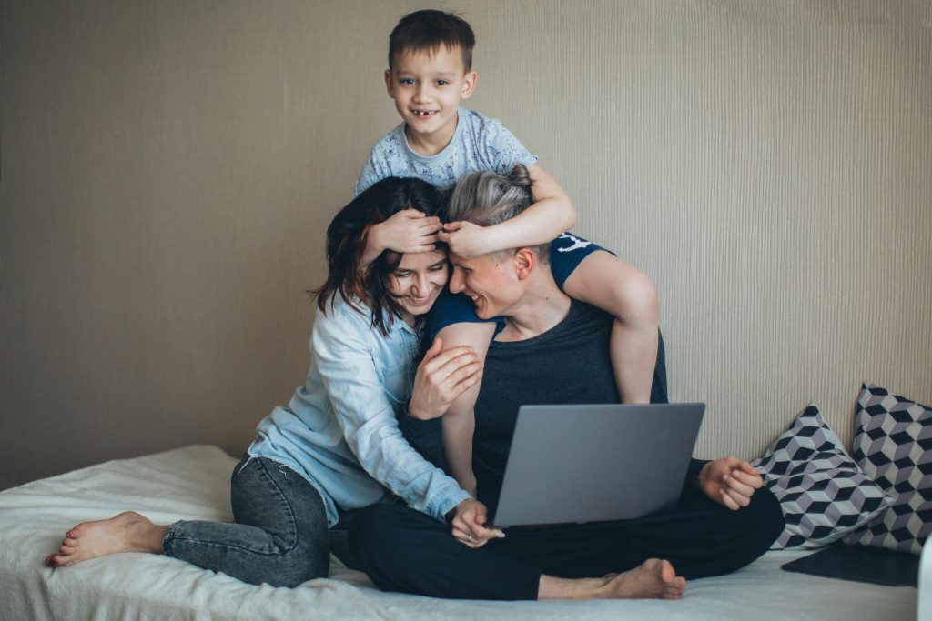 A man working remotely with his wife and kid hugging him